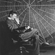 Imagen: Tesla frente a la espiral de la bobina de su transformador de alto voltaje. Wikimedia Commons